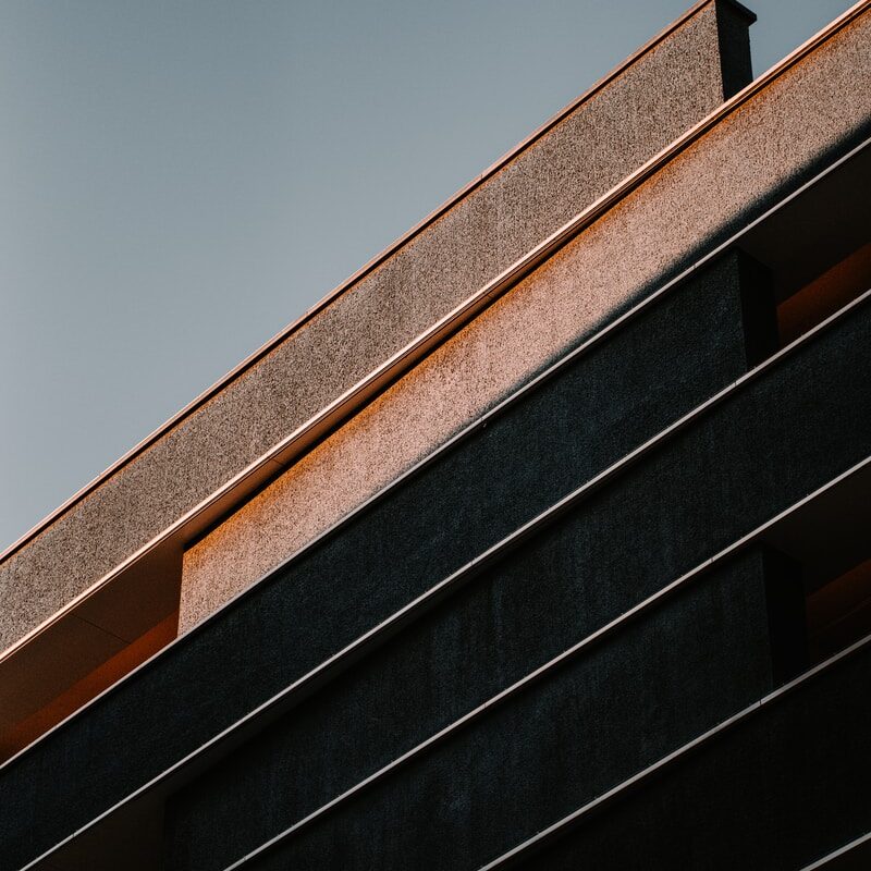 A close-up view of a modern building’s exterior, crafted by a specialty contractor, shows geometric lines and shadows against a clear sky.