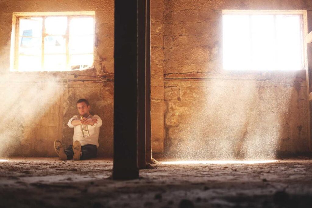 A person sits on the floor by a wall in a dusty, sunlit room that looks recently restored by a specialty contractor.